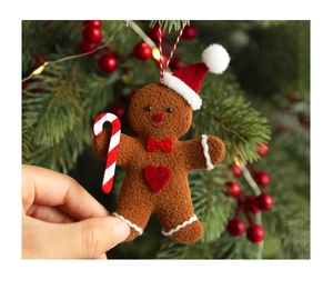 Detailed view of felt gingerbread man ornament held by hand against a festive tree background