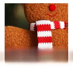 Close-up of a festive red and white striped knitted scarf on a plush gingerbread man