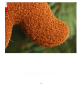Detailed close-up of brown plush gingerbread man ornament with festive red and white trim