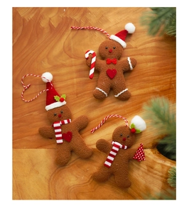 Detailed view of three gingerbread man ornaments with festive hats on wooden background