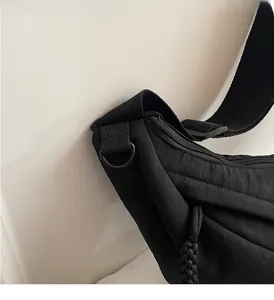 Detalle del bolso bandolera de nailon con correa de tela reforzada y anilla en D metálica