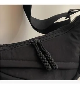 Detalle de bandolera de nailon con cremalleras dobles suaves y tiradores de cuerda trenzada