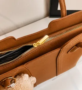 Gros plan sur la fermeture éclair dorée du sac cabas en cuir avec doublure rayée