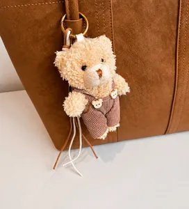 Détail d'un pendentif ours en peluche avec salopette rayée sur un sac à main marron