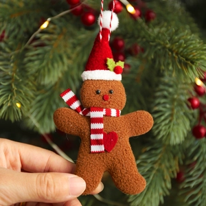 Three-piece gingerbread man ornaments set with red hats and scarves on a Christmas tree