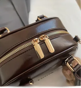 Macro view of smooth dual golden metal zippers on dark brown polished leather bag