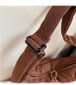 Détail d'une bandoulière en toile marron réglable avec boucle en plastique noir pour sac à main