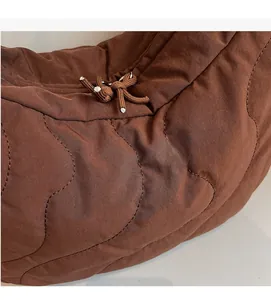 Gros plan du sac bandoulière matelassé marron avec coutures vagues et détail de cordon