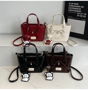 Detail shot of four small tote bags in red, white, black, and brown with bow details