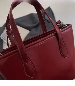 Detailed close-up of dark red leather handbag handles with teardrop stitching accents