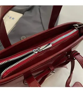 Detailed close-up of smooth silver zipper and glossy burgundy leather on a bucket bag