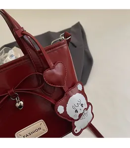 Detail of red glossy bucket bag with heart pendant and cute bear charm accessories