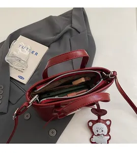 Detail view of red leather bucket bag interior with items and cute bear charm