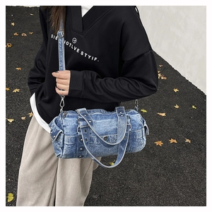Foto estilo urbano de un bolso bowling de mezclilla con remaches metálicos y correa ajustable