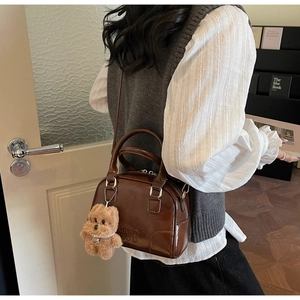Detailed side view of vintage brown leather bowling bag with cute puppy plush charm