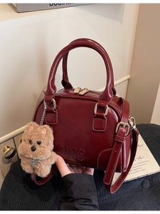 Deep red patent leather bowling handbag with plush puppy charm and gold hardware