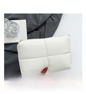 Detail shot of white quilted nylon clutch featuring a metal zipper and soft padded texture