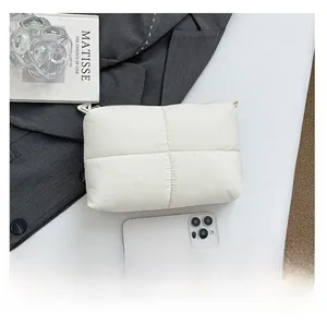 Detailed view of a white quilted down clutch bag showing size compared to a smartphone