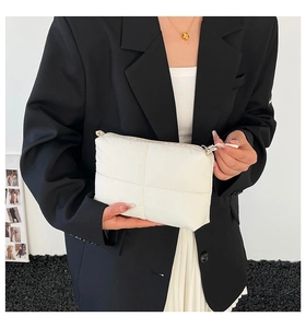 Detail of white quilted clutch bag featuring cross-grid stitching and zipper closure