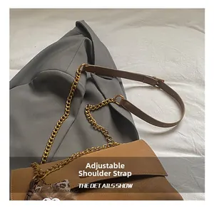 Detalle de bolso bandolera marrón mate con cadena dorada y correa de piel ajustable