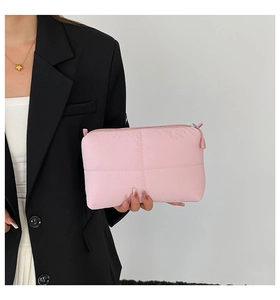Detail of pink quilted clutch bag featuring soft nylon material and zipper closure