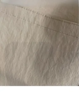 Gros plan du tissu beige du sac cabas montrant les coutures durables et la texture fine
