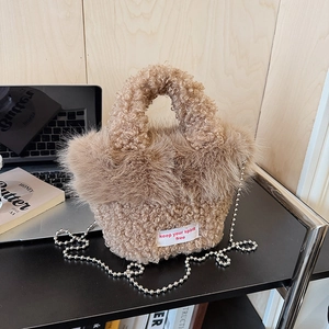 Détail du sac à main en peluche marron clair avec écusson blanc et bandoulière en chaîne
