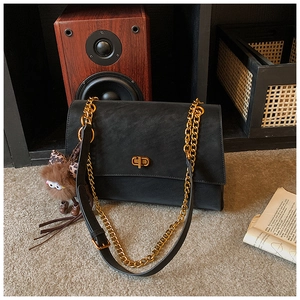 Detalle de bolso bandolera vintage negro con cadena dorada y colgante de peluche