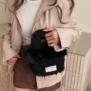 Détail d'un sac à main en peluche noire avec bandoulière chaîne et étiquette tissée douce