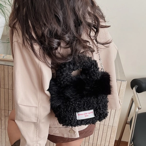 Détail du sac à main noir en peluche avec chaîne argentée et étiquette brodée