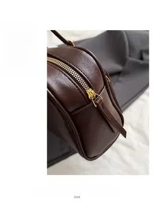 Close-up of golden zipper and smooth oily leather texture on brown shoulder bag