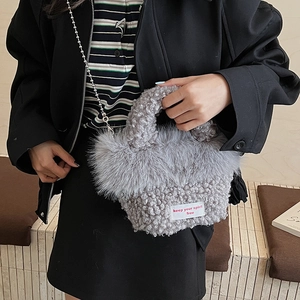 Détail d'un sac à main en peluche grise avec bordure duveteuse et chaîne argentée