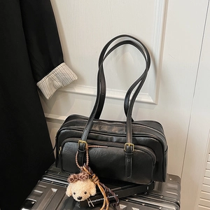 Detail of black faux leather shoulder bag with dual zipper compartments and puppy charm