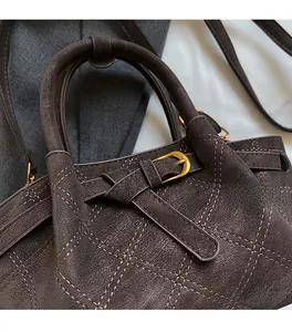 Detail der grauen Beuteltasche mit mattierter Textur, Rautensteppung und Messingschnalle