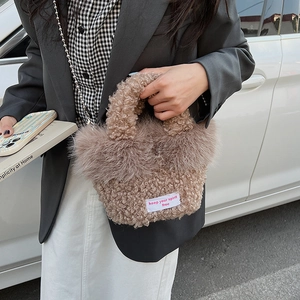 Détail du sac à main en peluche marron avec étiquette tissée blanche et chaîne à billes