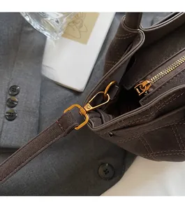 Detail der dunkelbraunen matten Eimertasche mit Goldbeschlägen und Steppmuster