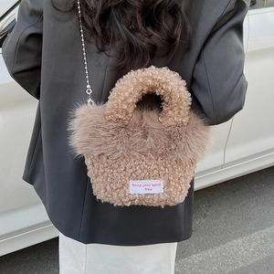 Détail du sac à main en peluche beige avec chaîne métallique et étiquette tissée rose
