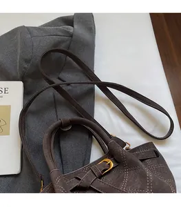 Detailansicht des glatten Leder-Schultergurts und der goldenen Schnalle an brauner Tasche