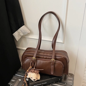 Detail of dark brown oil wax leather shoulder bag with vintage buckles and plush charm