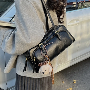 Detail of black vintage shoulder bag with golden hardware and plush teddy charm