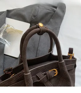Detail der dunkelbraunen Matten Beuteltasche mit Steppmuster und Goldbeschlägen