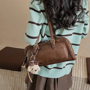 Detailed side view of vintage brown oil wax leather shoulder bag with plush dog charm