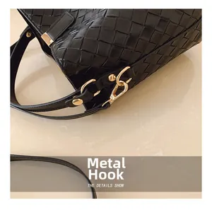 Macro detail of the golden hardware hook and black woven leather texture on bucket bag