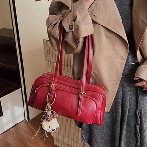 Close-up of vintage red underarm bag with zipper pockets and a cute plush bear charm
