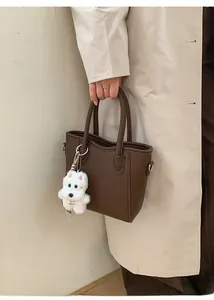 Vue détaillée du sac à main marron foncé avec texture litchi et un charme de chiot blanc