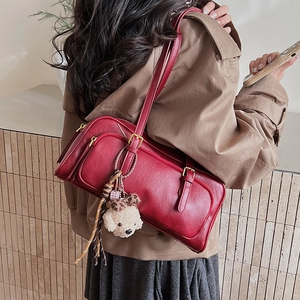 Close-up of vintage dark red shoulder bag with oil wax finish and cute bear charm