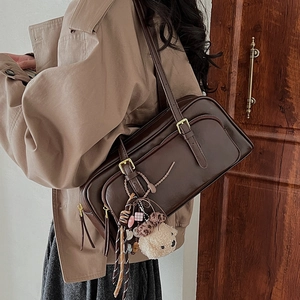 Detail of vintage oil wax leather shoulder bag with plush bear charm and golden zipper
