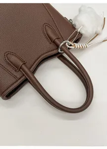 Vue détaillée du sac à main en cuir marron foncé avec ses poignées rondes et souples