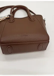 Détails de la base ovale renforcée et des ferrures argentées sur un sac en cuir marron