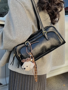 Retro black leather underarm shoulder bag with plush puppy charm on a model in a wool coat